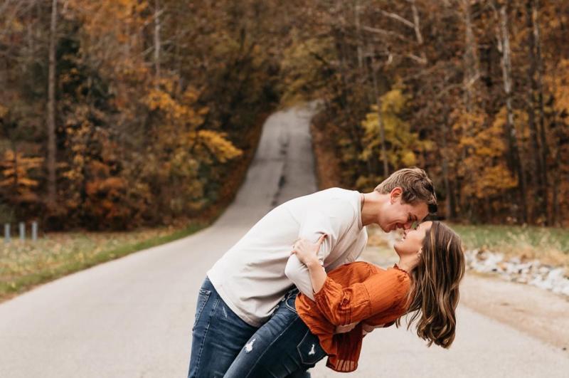 A couple posing in the middle of a road in the Hoosier National Forest during fall