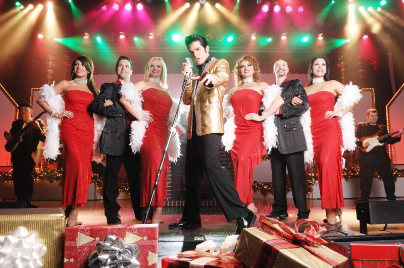 An Elvis impersonator stands on stage in front of a line of four women and two men during Legends in Concert