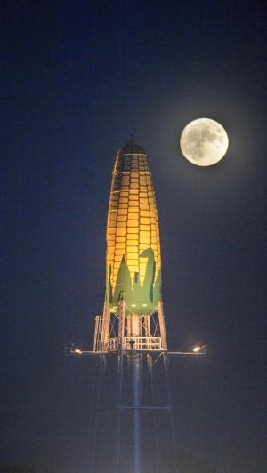 Ear of Corn Water Tower at night with full moon behind it
