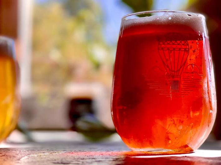 A glass of beer in a hot air balloon glass sits on a table