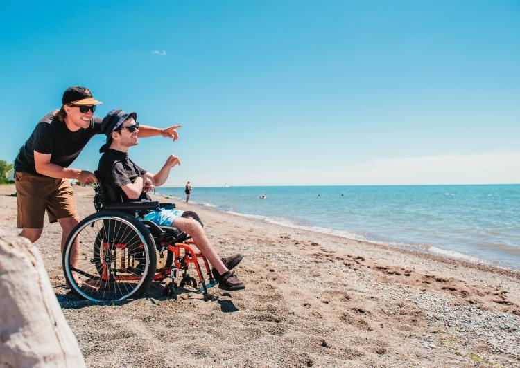 Two men, one in a wheelchair on the beach