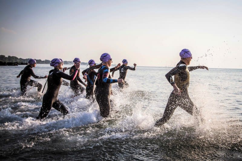 Swimmers race into the water during the Maple Grove Triathlon