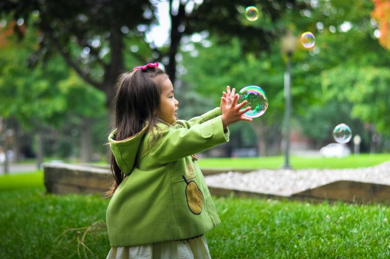 Small child chases bubbles in a park 