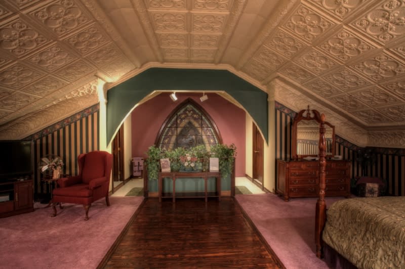 Upper room of 19th century church turned into a B&B with pink carpeting and molded ceiling.