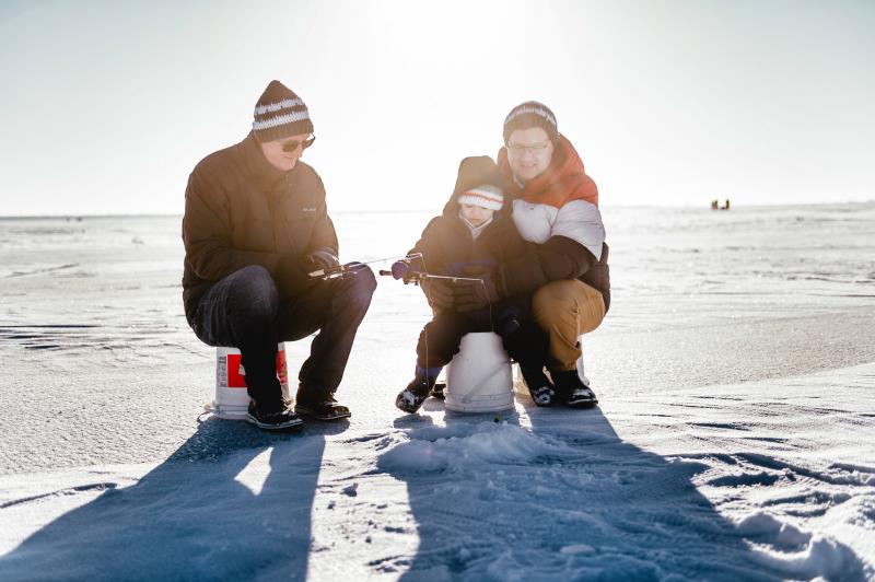 two parents and child ice fishing