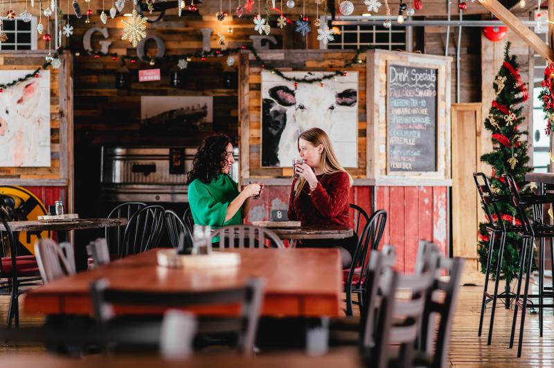 two women drinking coffee in a room decorated for the holidays