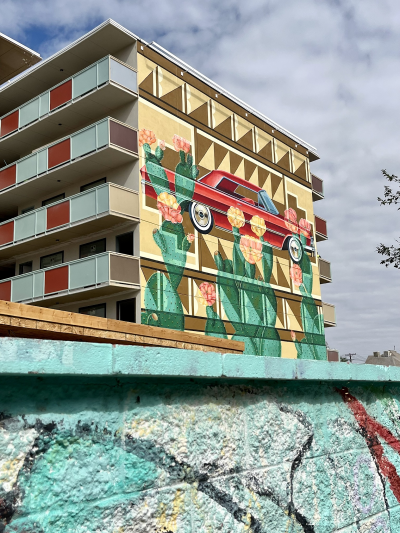 Mural of a lowrider and prickly pear mural on the side of ARRIVE Hotel.