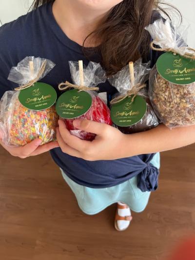 Woman holding arm full of candied apples at Scootys Apples