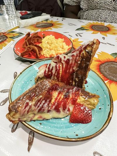 French toast on a green plate with eggs and bacon on a red plate at The Flying Biscuit in Huntsville, Alabama