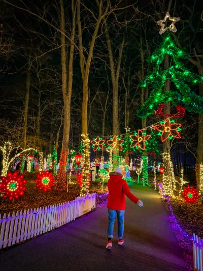 someone walking through Rocky Ridge Park during Christmas Magic surrounded by millions of twinkling holiday lights in their annual display