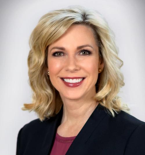 Headshot of a smiling woman wearing a black jacket and maroon shirt