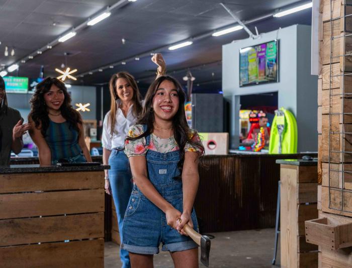 A girl is getting ready to throw an axe inside of the axe throwing spot in Xtreme Arcade in Elizabethtown, Kentucky