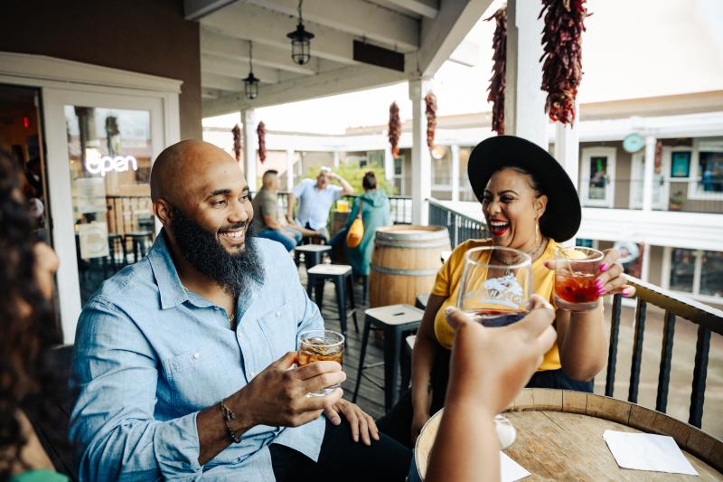 Two people laugh with others drinking wine at Downshift Brewing
