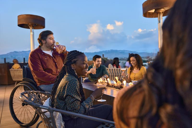 A group sips drinks and chats at Level 5 Rooftop Bar at Hotel Chaco