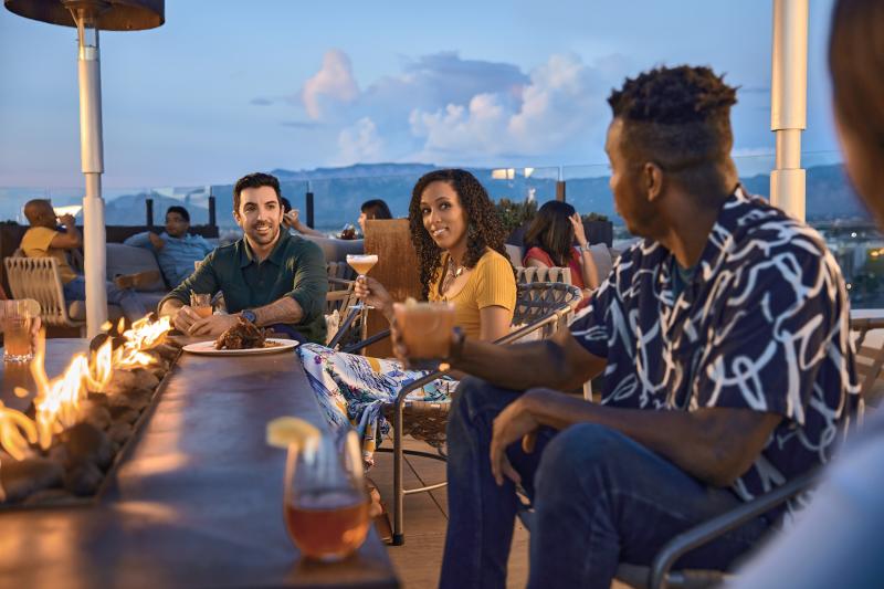 Three people chat around a table at Level 5 Rooftop Bar in Hotel Chaco