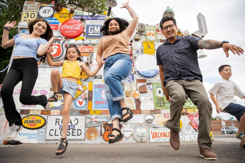 A family jumps in front of a wall of signs
