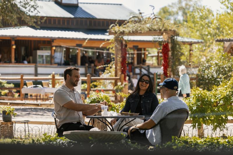 Three people sit at a table outside at Bike In Coffee.