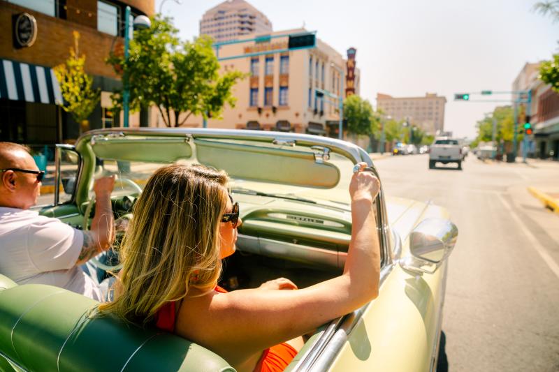 A man drives a woman in the passenger street down Central Ave. in Downtown Albuquerque.