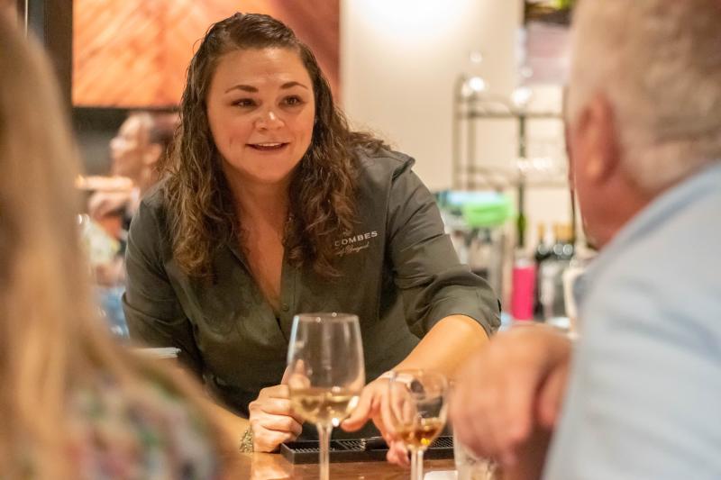 A server at D.H. Lescombes talks to two customers.