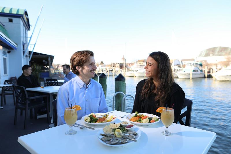 A man and woman eat seafood by the water's edge