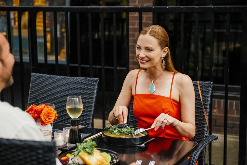 Woman in red sundress eating at an outdoor table