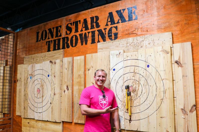 Photo of person next to axe on a bullseye at Lone Star Axe Throwing