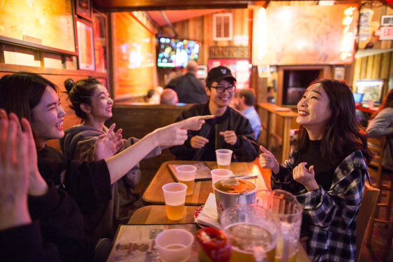 A group of people having drinks and playing the game “Sink the Biz” at Nick’s English Hut 