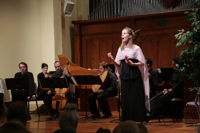 A woman singing on stage in periodical costume