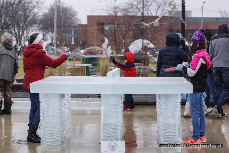 Two kids playing ping pong on a table carved of ice at Freezefest