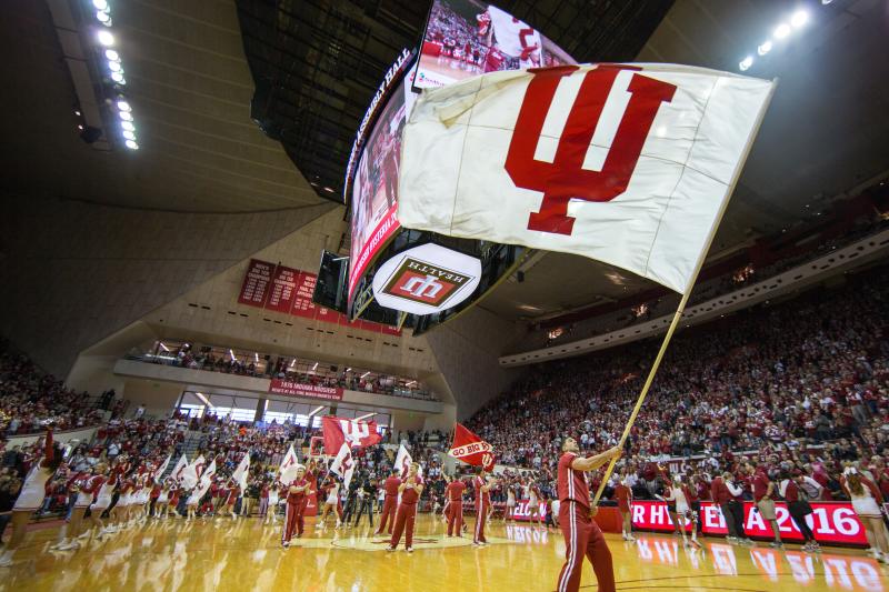 A male cheerleader waving a huge IU flag during a basketball game