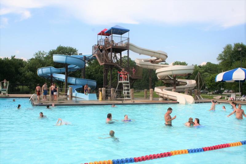 People enjoying Bryan Park's pool and waterslides on a summer day