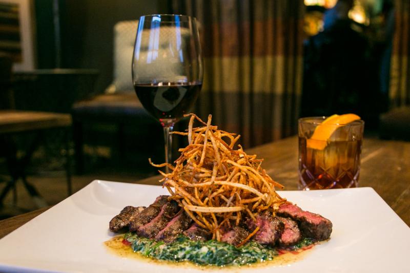 A glass of wine, a cocktail, and a steak dish from C3