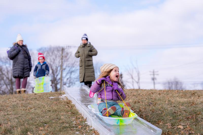 A little girl sledding down the ice luge at Freezefest