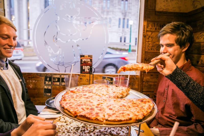 A slice of cheese pizza being served at a table at Mother Bear's Pizza