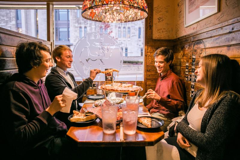 A group of four people sharing a pizza at Mother Bear's Pizza