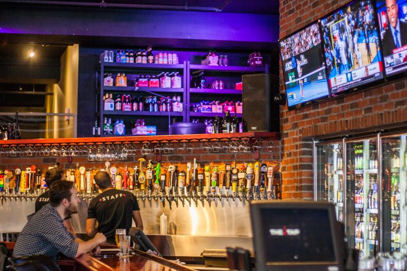 A man watching several TVs from the bar at The Tap