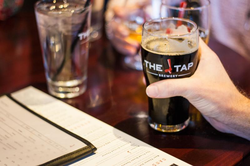 A person holding a glass of beer at The Tap