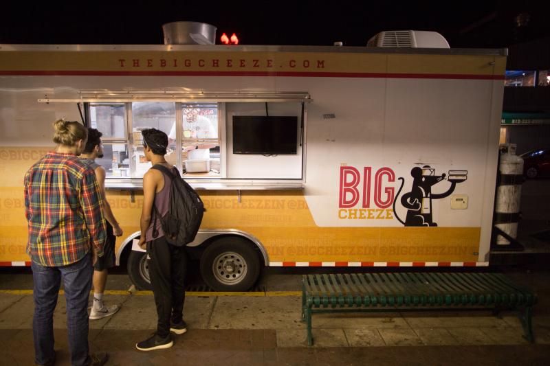 Three guys standing in line to order from The Big Cheeze food truck