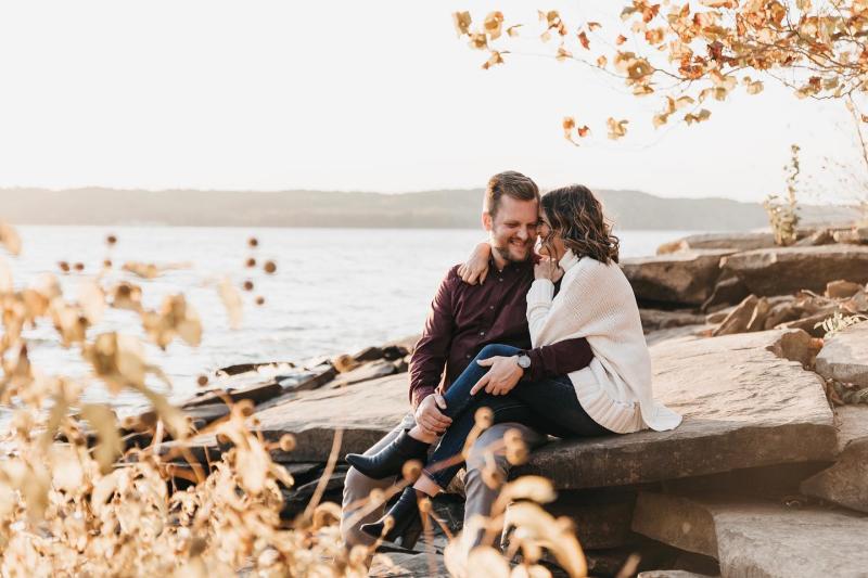 A couple sitting on the rocky shore of Monroe Lake during fall