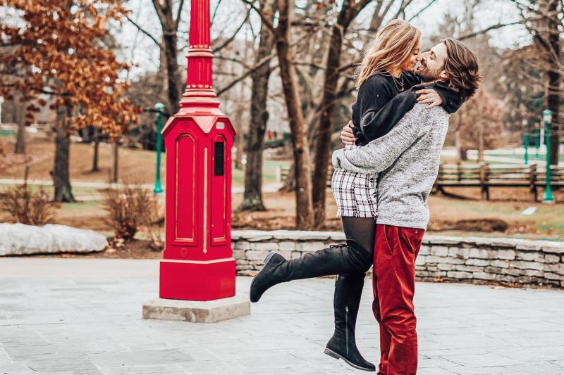 A couple embracing in front of one of Indiana University's signature red clocks