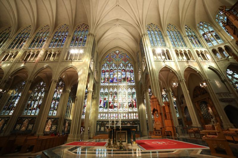 A photo of the altar at Cathedral Basilica of the Assumption with multiple stained glass windows behind.