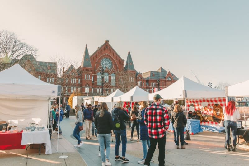 Image is of people shopping at vendor tents during the day in the winter with Cincinnati Music Hall in the background.