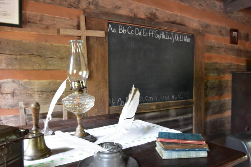 old books, a quill and lantern with a chalkboard in a log building