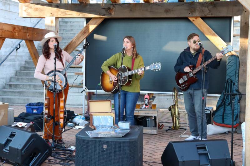 Three musicians performing at a small outdoor venue