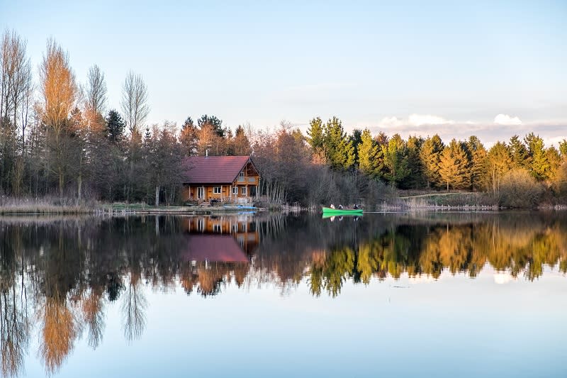 A cabin looks over a lake on a bright winter day at Log House Holidays