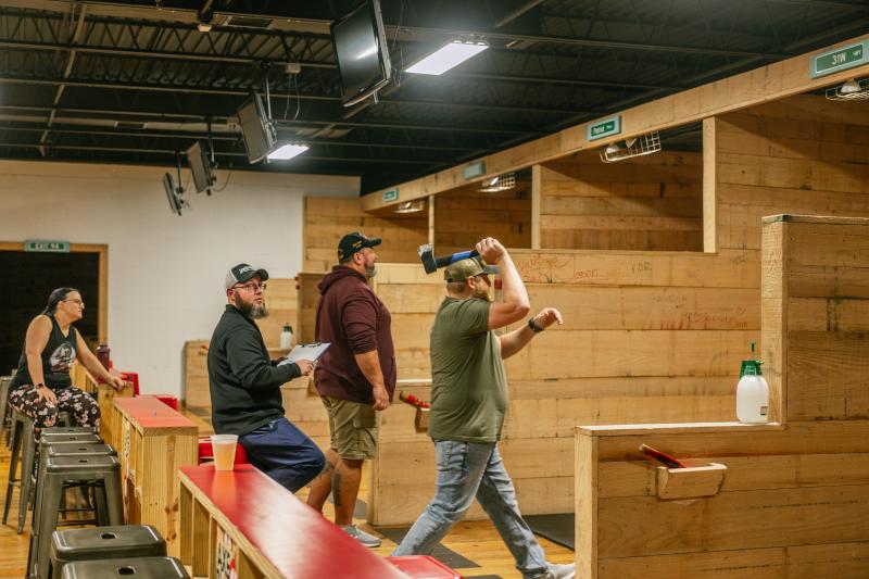 people lined up throwing axes at axe play