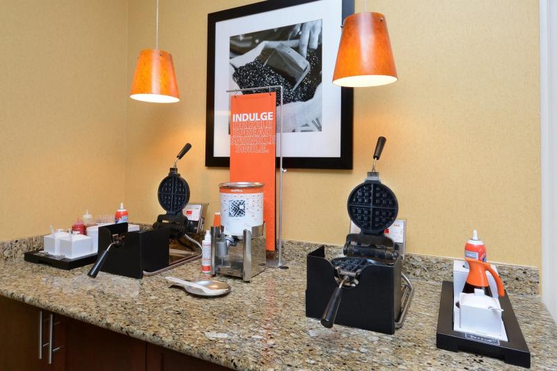 Close-up of a hotel breakfast area with waffle makers, syrup, and toppings ready for guests to create their own waffles in Fayetteville, North Carolina.