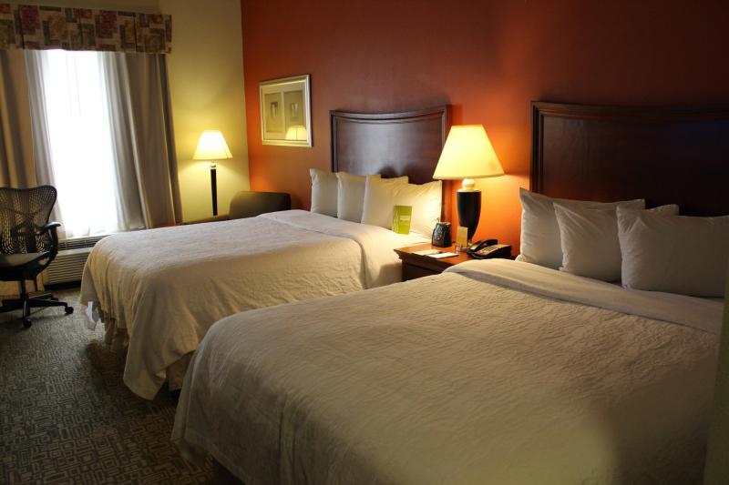 Cozy hotel room in Fayetteville, North Carolina with two neatly made double beds, soft lighting, and a comfortable seating area.