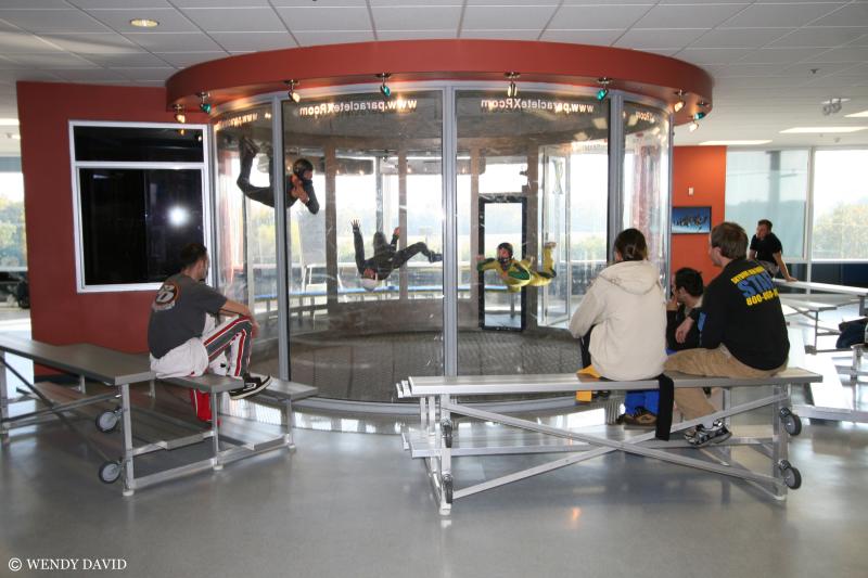 A family watches from bleachers as participants float inside the wind tunnel at Paraclete XP Indoor Skydiving in Cumberland County. The indoor adventure lets visitors experience the thrill of freefall in a safe, climate-controlled setting.