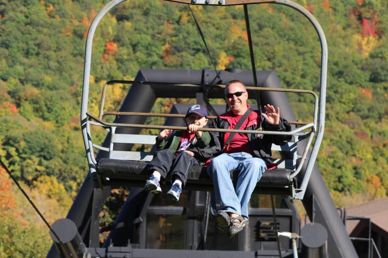 Father and son on the ski lift surrounded by fall foliage